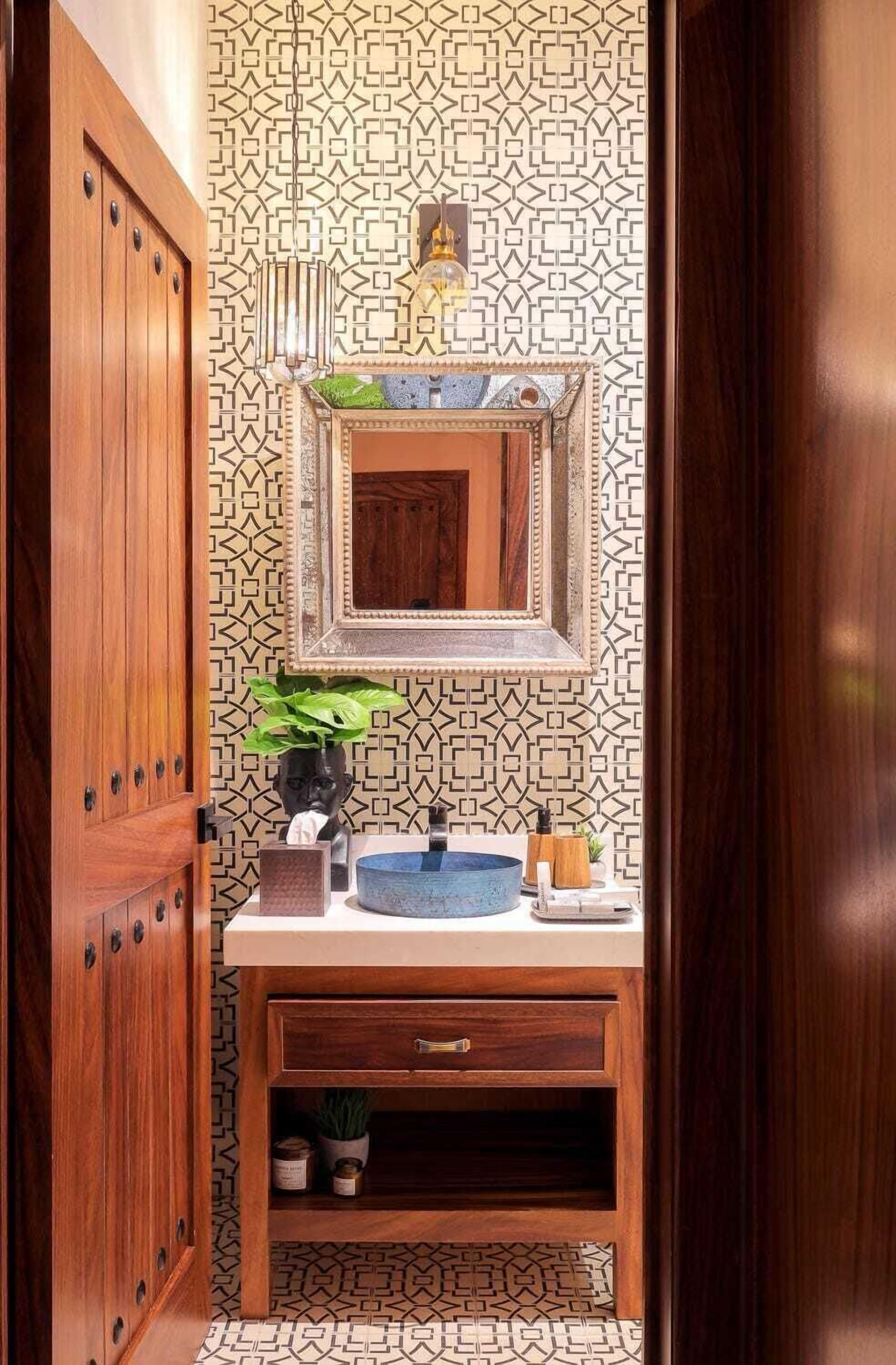 Une salle de bain avec un meuble-lavabo en bois, un miroir, un évier et un mur décoré d’un motif.