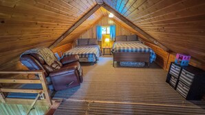 A cozy attic bedroom with two beds, a leather chair, and a small table. - Cabin with private dock and large yard space! (Butternut)