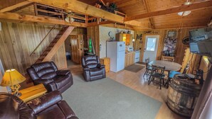 A cozy cabin interior with a dining area, kitchen, and a staircase leading to an upper level. - Cabin with private dock and large yard space! (Butternut)