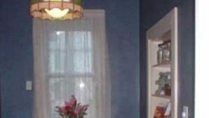 A dining area with a wooden table and chairs, a vase with flowers, and a hanging light fixture. - Aunt Jane's #1 Downtown Put in Bay up to 12 guests (Put-in-Bay)