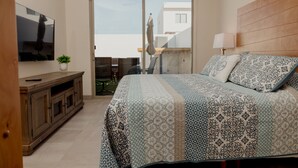 Ein Schlafzimmer mit Bett, Fernseher, einem Holzschrank und einem Balkon mit Aussicht.