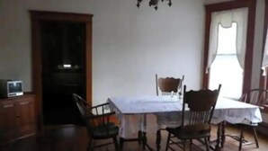 Una sala da pranzo con tavolo e quattro sedie, un lampadario e un televisore su un mobile.