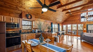 Een ruime houten chalet met keuken, eethoek en terras.