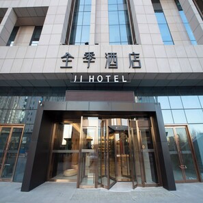 A hotel entrance with a modern design, featuring a glass facade and a revolving door.