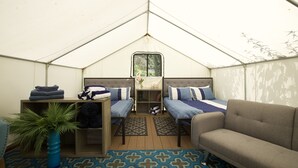 A tent with two beds, a sofa, a small table, and a potted plant. - Surrey Resort  (Guerneville)