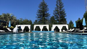 A swimming pool with clear blue water, surrounded by white canopies and lounge chairs. - Surrey Resort  (Guerneville)