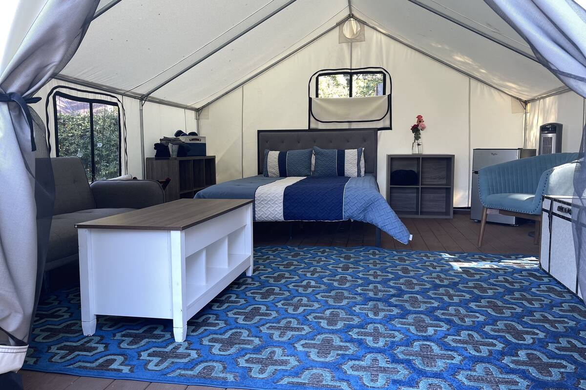 Un hébergement en tente comprenant un lit, un bureau, une chaise et une petite kitchenette.
