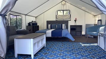 Alojamiento con tienda de campaña, cama, escritorio, silla y una pequeña kitchenette.