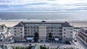 Ein mehrstöckiges Hotel mit Parkplatz vor der Tür, in Strandnähe mit Blick auf den Ozean.