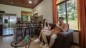 Una sala de estar moderna con sofá, una mesa de centro y una cocina al fondo.