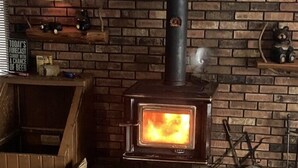 Un poêle à bois à l’extérieur en briques, avec une cheminée et un feu allumé.