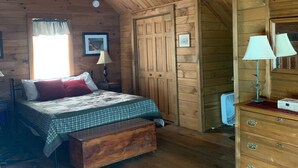 A wooden cabin bedroom with a bed, dresser, and ceiling fan.