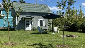 A house with a green roof, a front door, and a small porch with two chairs.