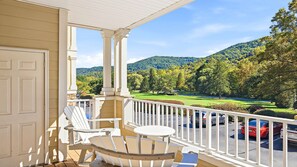 A porch with white chairs and a table, overlooking a golf course and forested hills. - Mountain View and 8th green! 70" TV, gas fireplace, Fast WIFI,Amenities included (Maggie Valley)