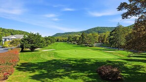 A golf course with a clubhouse, trees, and a mountain backdrop. - Mountain View and 8th green! 70" TV, gas fireplace, Fast WIFI,Amenities included (Maggie Valley)