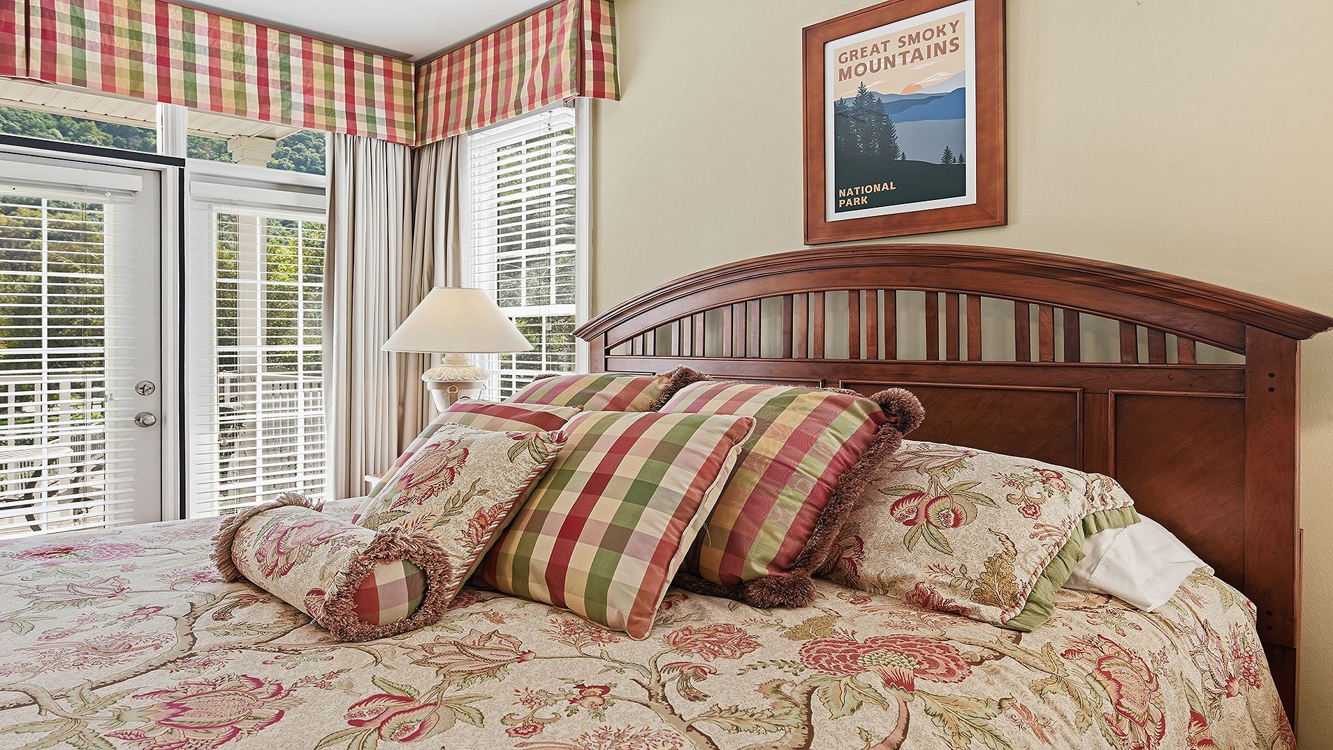 A bedroom with a bed, curtains, a lamp, and a framed picture on the wall.