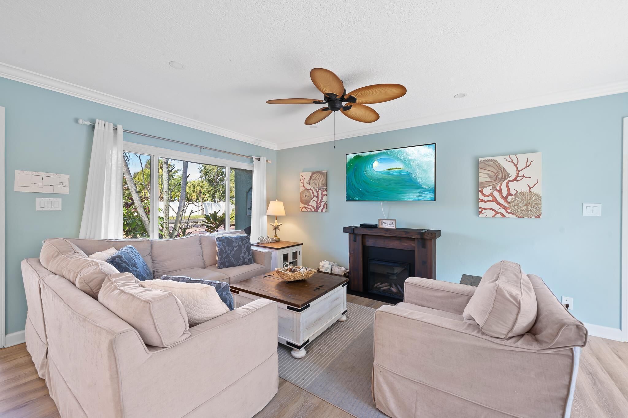 A living room with a beige sofa, a coffee table, a TV, and artwork on the wall.