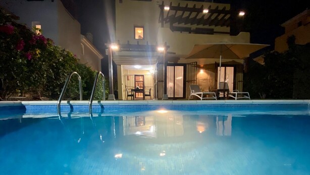 Une piscine offrant une vue dégagée sur l’espace aménagé au bord de la piscine, comprenant notamment un transat et une table avec des chaises.
