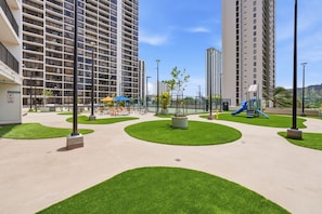 A residential area with high-rise buildings, a playground, and a well-maintained lawn.