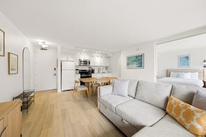 A modern apartment with a kitchen, dining area, and a living room with a sofa. - Waikiki Banyan: 1 BD, Parking, AC, Unit Wash/Dryer (Honolulu)