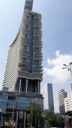 Un immeuble moderne de grande hauteur, doté d’une façade incurvée, de grandes fenêtres et de balcons.