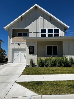A two-story house with a garage, a front yard with grass, and a sign that reads "Little Cottage 1975".