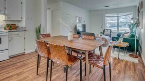 Una cocina moderna con armarios blancos, una mesa de comedor de madera y un ventanal grande.