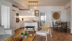 A modern kitchen with white cabinets, a wooden dining table, and a chessboard. - Alekos Beach Houses-Eternity (Kefalonia)