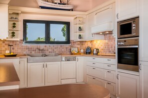 A modern kitchen with white cabinetry, a large window, and built-in appliances including a microwave and oven.