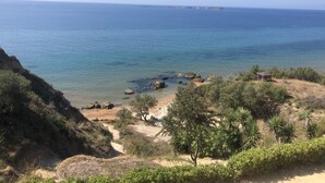 A coastal landscape with a clear view of the sea, rocky outcrops, and a small structure on the beach. - Alekos Beach Houses-Eternity (Kefalonia)