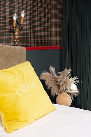 A bed with a yellow pillow, a decorative wall with a plaid pattern, and a vase with dried flowers. - Peer Boutique Hotel Tel Aviv (Tel Aviv)