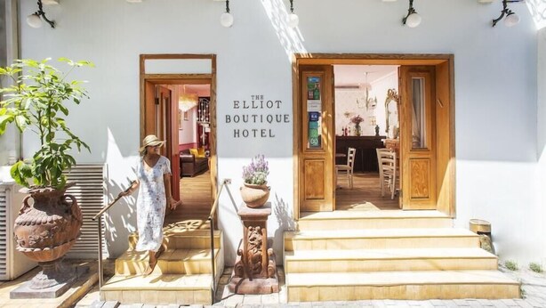 De ingang van Hotel Elliot Boutique, met een bord, houten treden en een potplant.