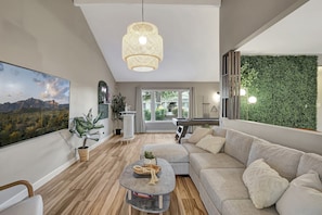 A modern living room with a large painting, a hanging light fixture, a green wall, and a pool table. - Scottsdale Gem - Pickleball/Pool/Jacuzzi/Golf 10mins to Kierland Commons (Scottsdale)