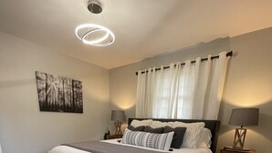Ein Schlafzimmer mit einem großen Bett, einem weißen Teppich, einem Bild an der Wand und zwei Nachttischlampen.