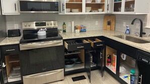 Eine moderne Küche mit Edelstahlgeräten, weißen Schränken und einer Arbeitsplatte aus Granit.