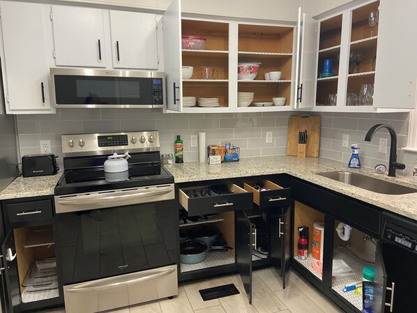 Una cocina moderna con electrodomésticos de acero inoxidable, gabinetes blancos y encimera de granito.