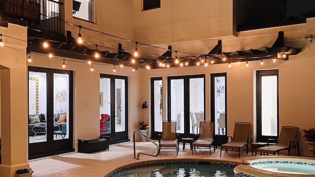 Ein Poolbereich mit Whirlpool, Sitzgelegenheiten im Freien und Lichterketten.