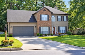 A two-story house with a garage, a front door, and a well-maintained lawn.
