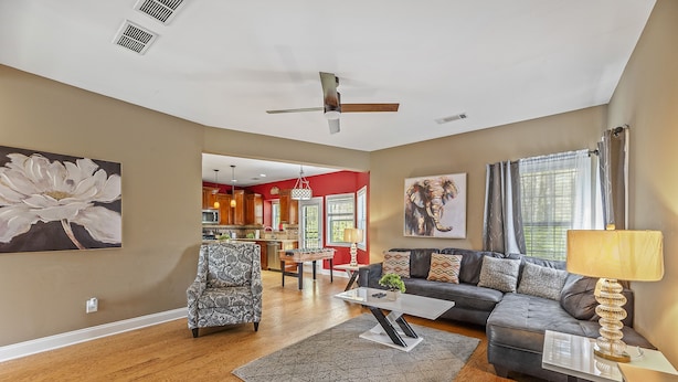 A spacious living room with hardwood flooring, a grey sofa, a patterned armchair, and a coffee table. - 4BDR Atlanta Retreat : Spacious Home with Office close to Airport (Atlanta)
