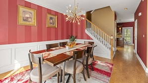 A dining area with a wooden table, chairs, a chandelier, and a staircase. - 4BDR Atlanta Retreat : Spacious Home with Office close to Airport (Atlanta)