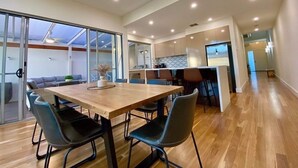 Une cuisine moderne avec un plan de travail en bois, un coin repas comprenant une table et des chaises en bois, et une grande porte-fenêtre coulissante donnant sur un balcon.