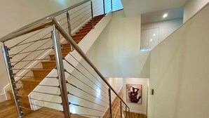 Un escalier moderne avec des marches en bois et des rampes en métal, menant à l’étage supérieur.