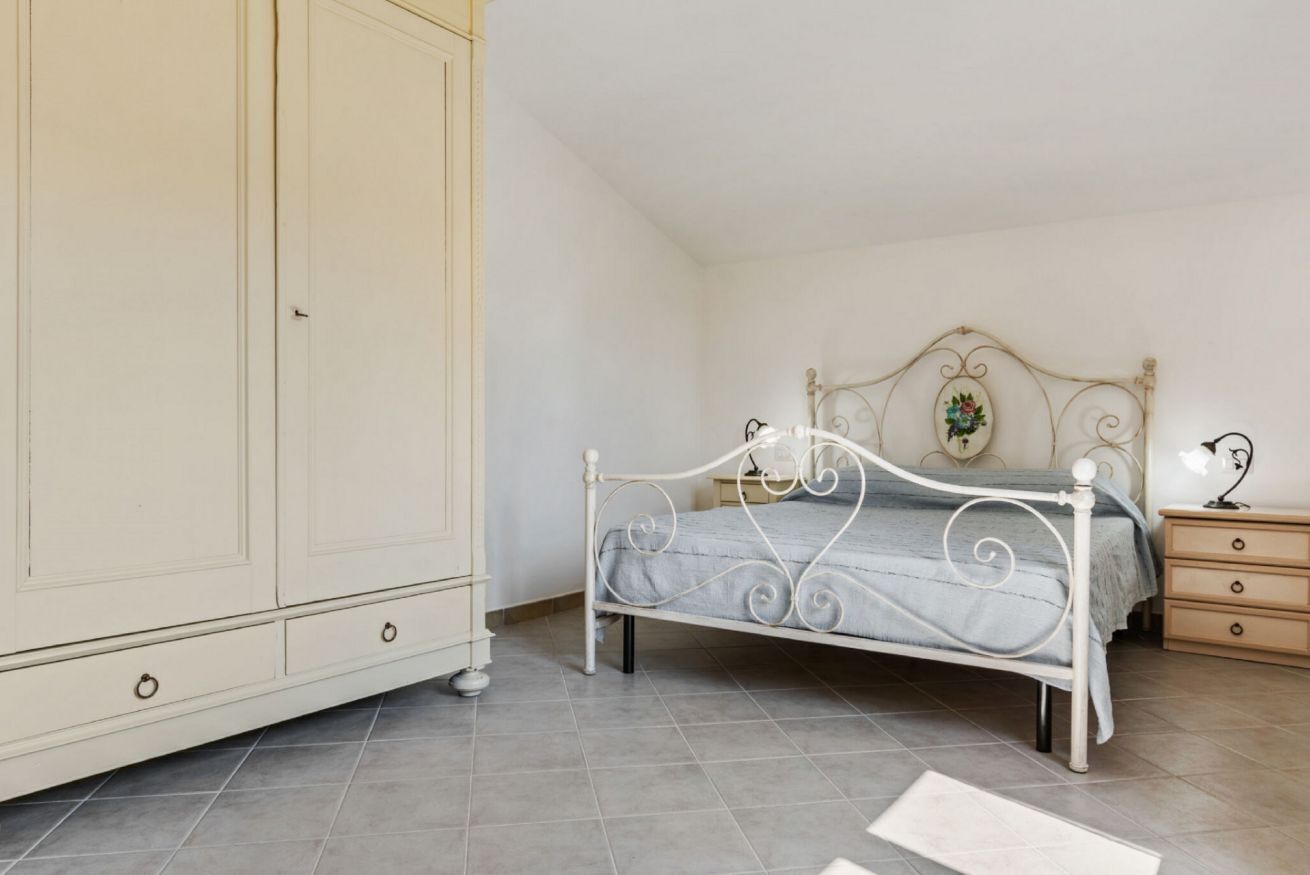 Un dormitorio con cama, armario, mesita de noche y cómoda.