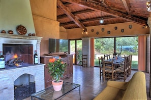 A spacious living area with a fireplace, television, dining table, and outdoor patio.