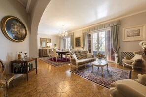 A spacious living room with a large sofa, a coffee table, and a dining area with a chandelier.