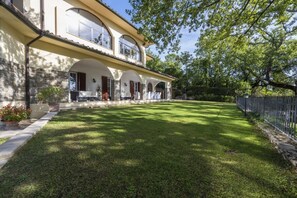 Une maison à deux étages avec une façade en pierre, de grandes fenêtres et une pelouse bien entretenue.