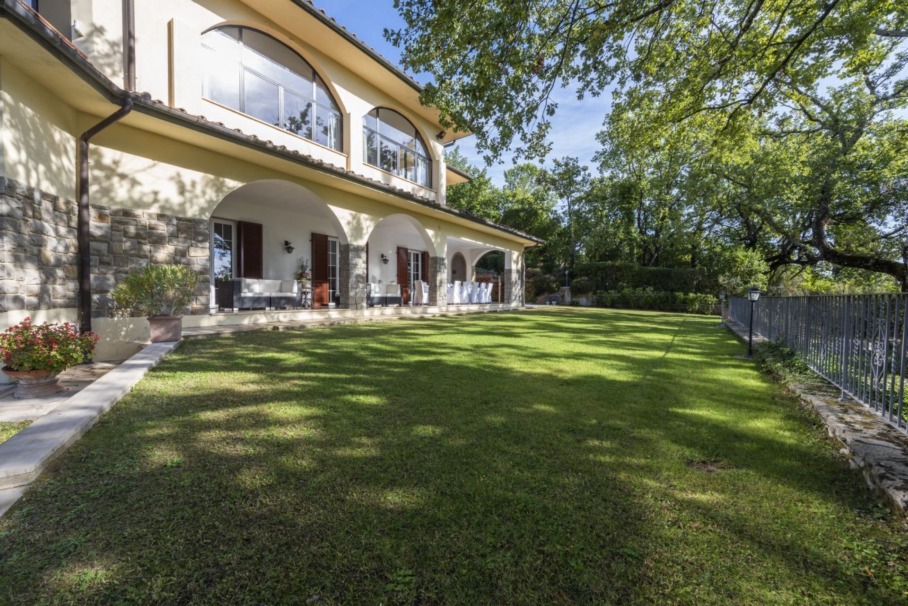 Una casa a due piani con facciata in pietra, ampie finestre e un prato curato.