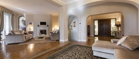 A spacious living room with a fireplace, sofas, and a large rug.