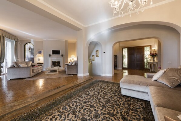 A spacious living room with a fireplace, sofas, and a large rug.
