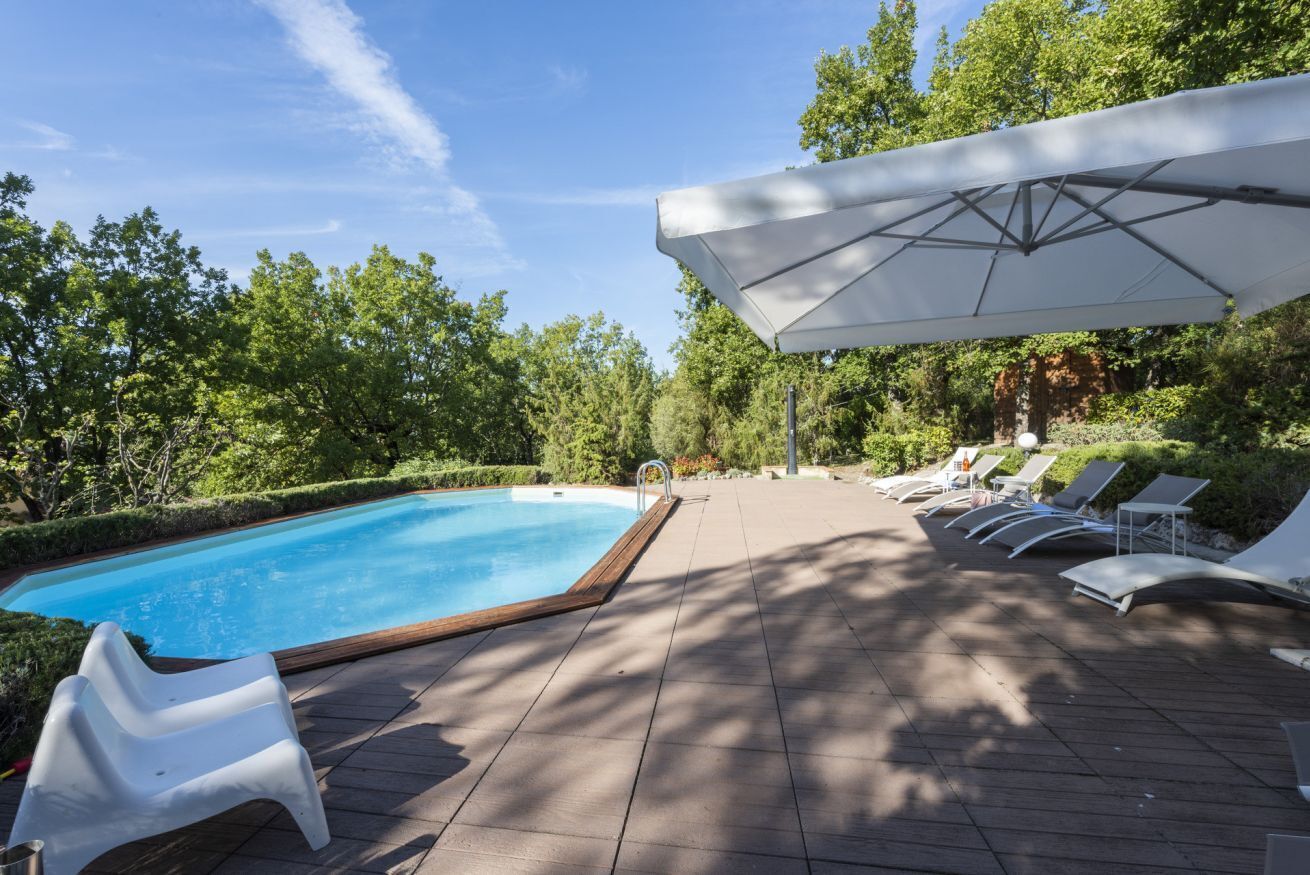 Una piscina con lettini e una zona ombreggiata.